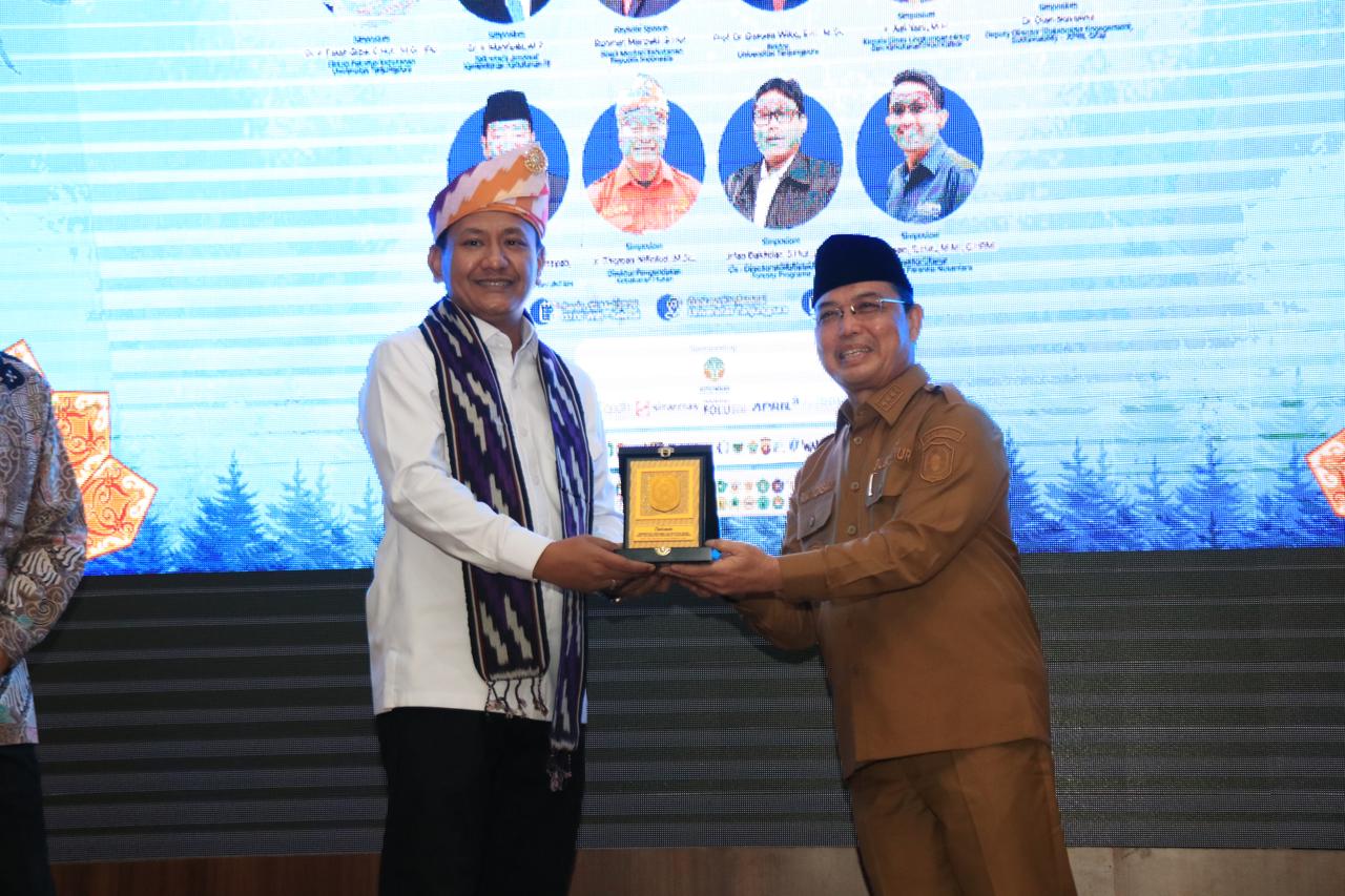 Gubernur Kalbar, Ria Norsan menyerahkan cenderamata kepada Wakil Menteri Kehutanan RI, Rohmat Marzuki saat pembukaan Konferensi Nasional Sylva Indonesia (KNSI) XXI di Universitas Tanjungpura, Senin (18/5/2026). Foto: Istimewa
