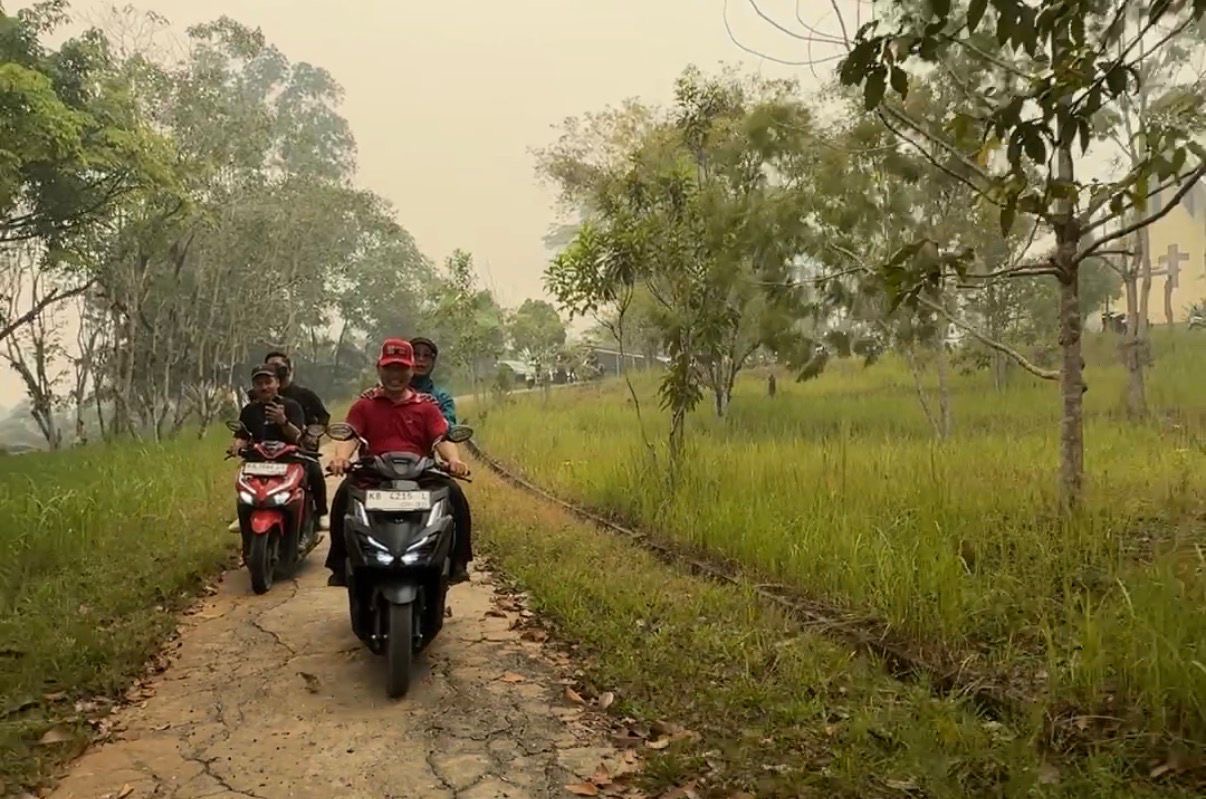 Gubernur Kalimantan Barat Ria Norsan mengendarai sepeda motor saat menyusuri jalan di Desa Serimbu, Kecamatan Air Besar, Kabupaten Landak, usai menghadiri kegiatan GMD ke-IV. Dalam kunjungannya, Norsan juga meninjau sejumlah lokasi yang menyimpan kenangan masa kecilnya. Foto: Istimewa