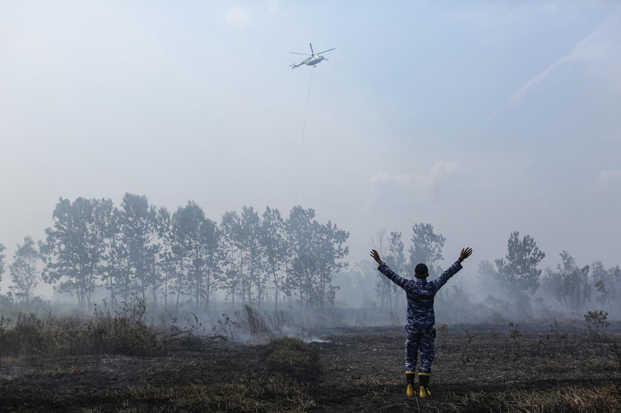Seorang prajurit TNI Angkatan Udara memberikan kode kepada helikopter water bombing untuk memadamkan kebakaran hutan dan lahan (Karhutla) di lahan gambut, Kota Banjar Baru, Kalimantan Selatan, Kamis (10/9/2026). ANTARA