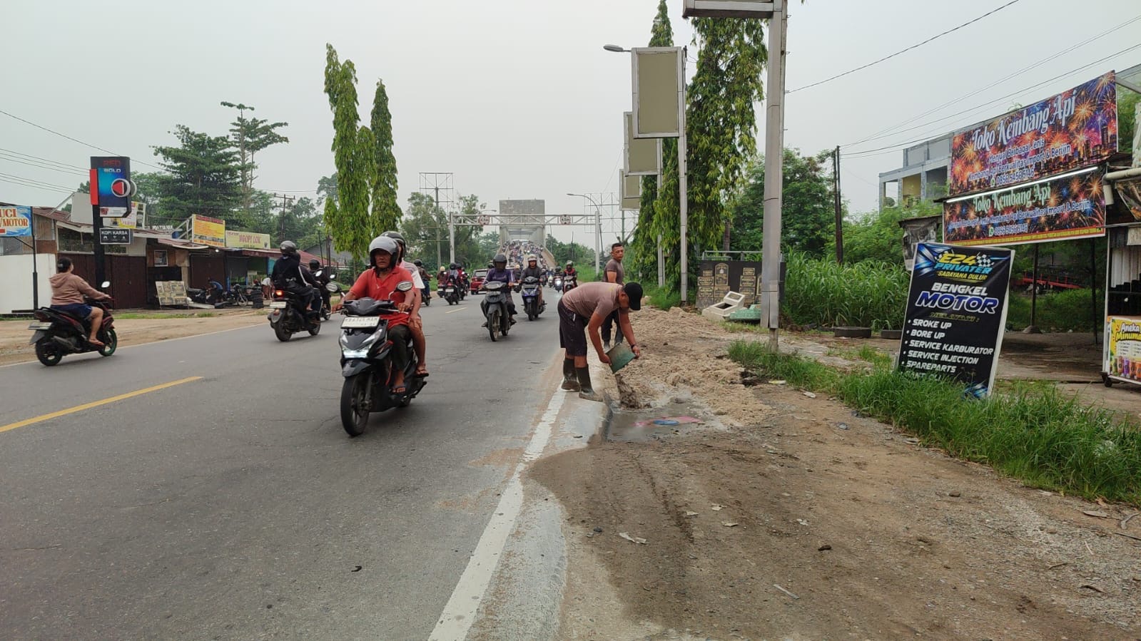 ua personel Satlantas Polres Kubu Raya, Aiptu Noval Suseno dan Aiptu Guntoro, menimbun lubang di bahu Jalan Mayor Alianyang, Kabupaten Kubu Raya, Kamis (22/10/2026), untuk mengurangi risiko kecelakaan bagi pengguna jalan. Foto: Istimewa